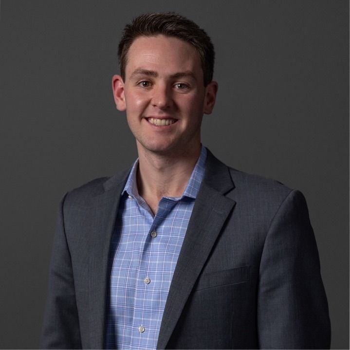 Richard Joseph Spinelli smiling in a studio headshot, grey jacket over a blue checked shirt